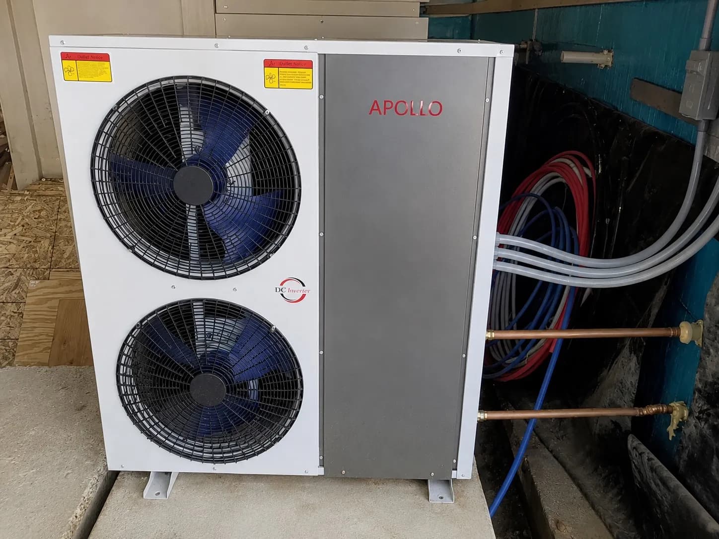 Apollo 5 ton air to water heat pump connected to copper piping and hydronic lines in a utility room.
