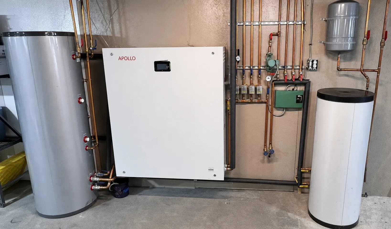 Apollo hydro station installed with buffer tank, expansion tank, pumps, and copper piping in a mechanical room.