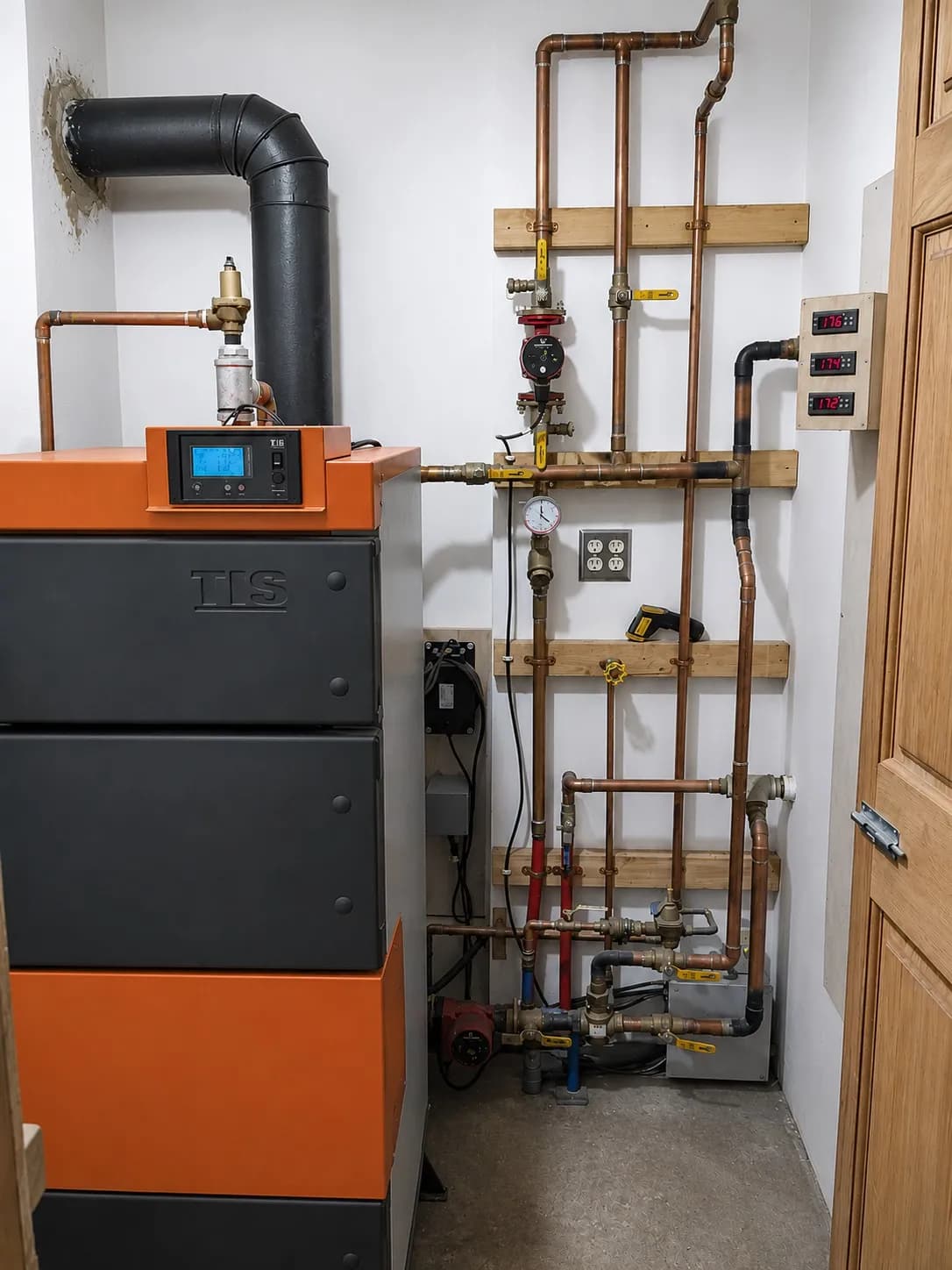 UNI wood boiler installed with copper hydronic piping, pumps, valves, and temperature controls.