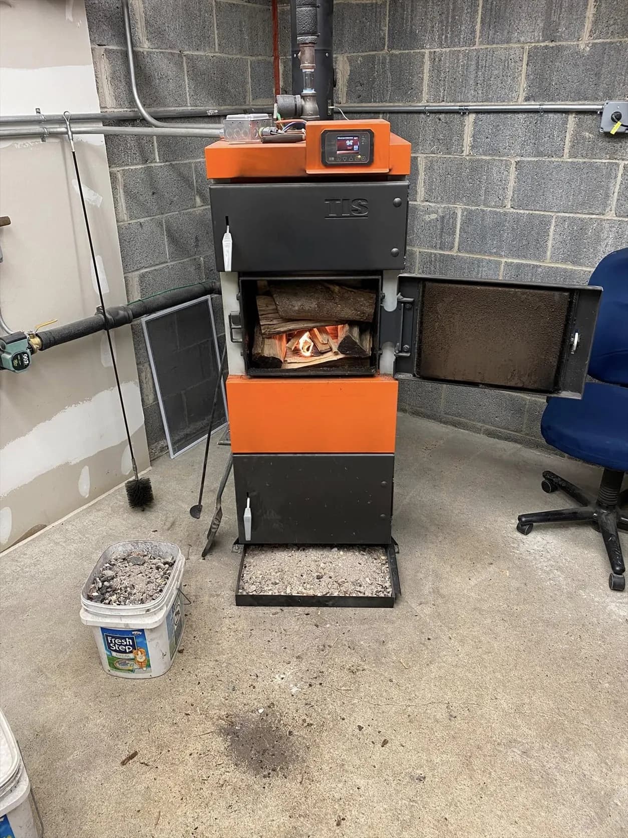 UNI wood boiler with its firebox door open, loaded logs, and a small flame inside.