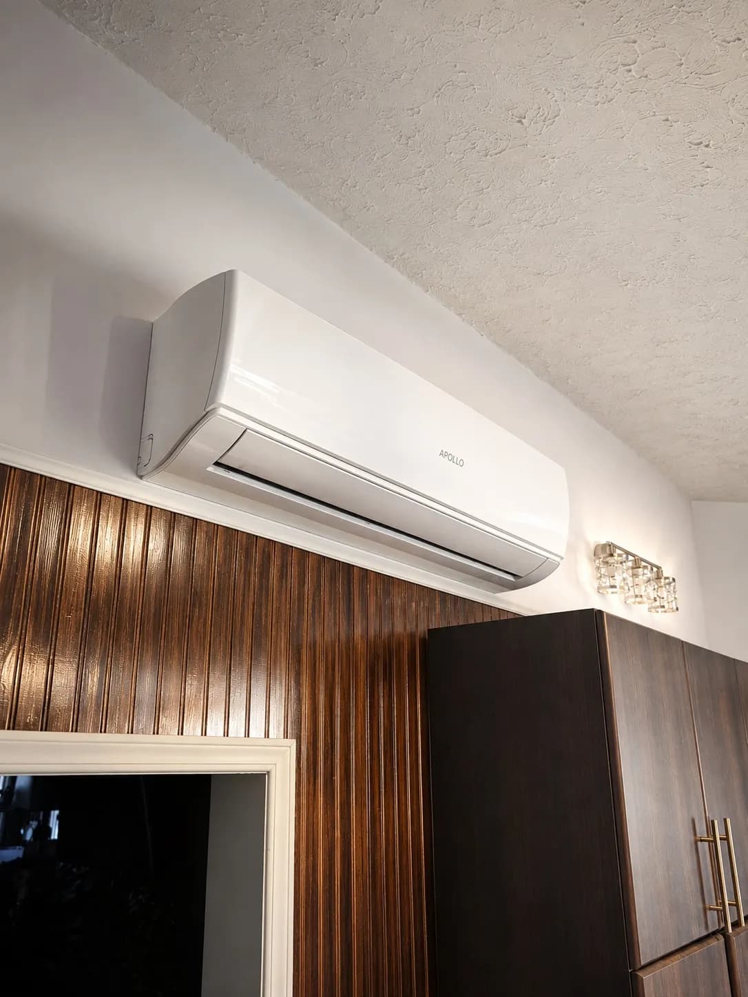 Apollo 3 ton wall fan coil installed above dark wood kitchen cabinets.