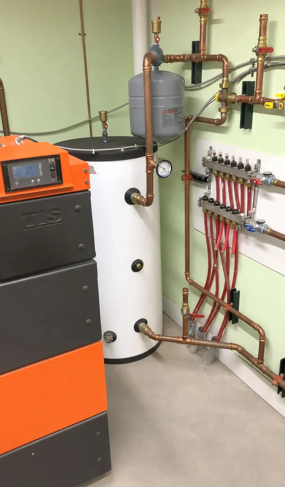 UNI wood boiler installation with water tank, copper piping, expansion tank, and manifold.
